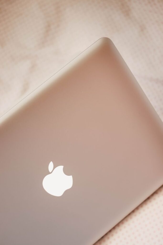From above of modern design netbook with smooth glowing surface on creased bed sheet in daylight in house